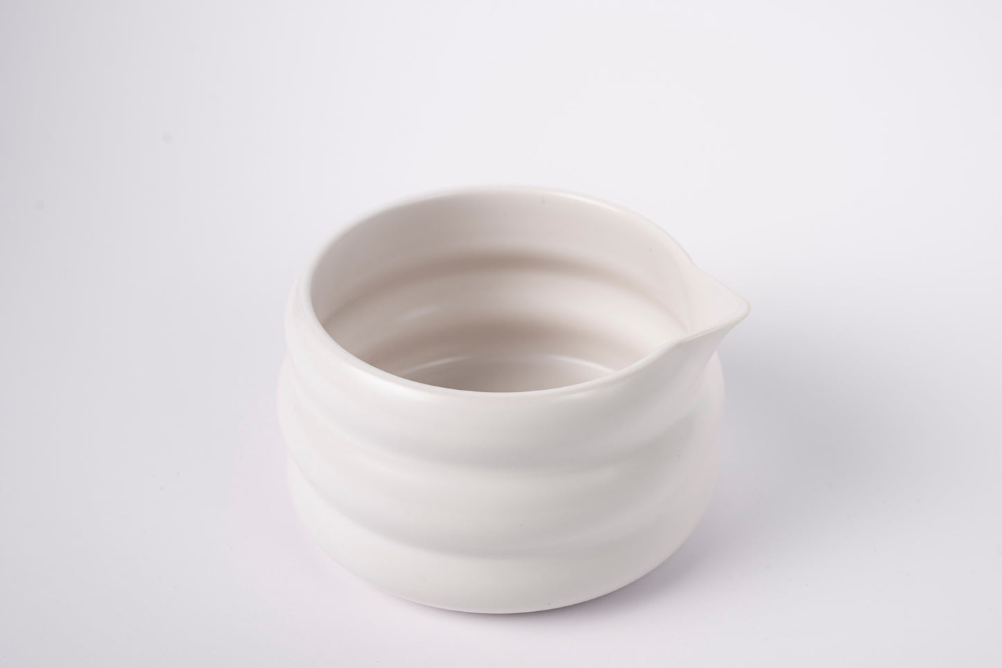Krēmīgi balta keramiska matcha bļoda no augšas uz balta fona