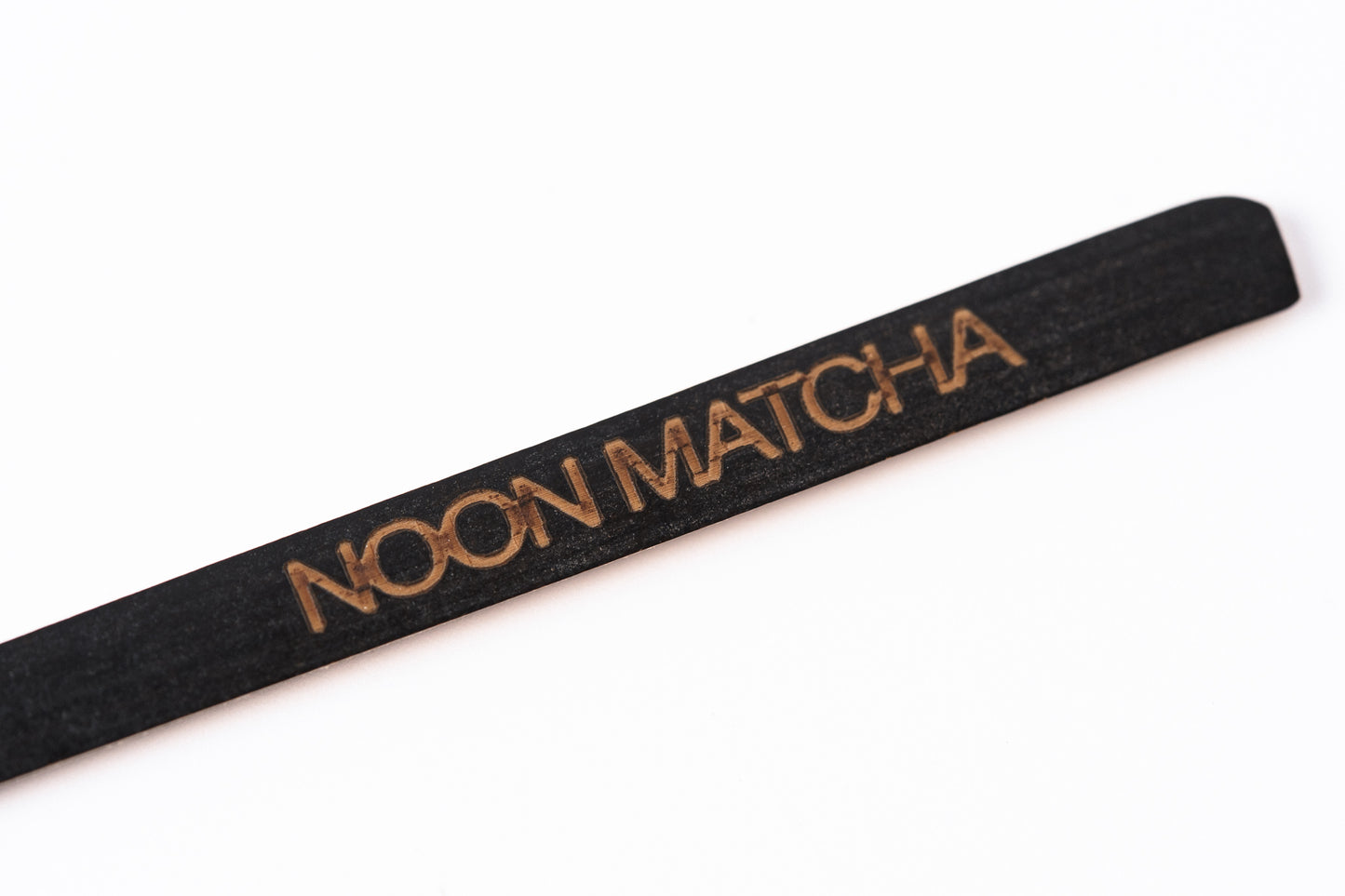 Tumši brūnas bambusas matcha karotītes ar NOON logo uz balta fona - beigas