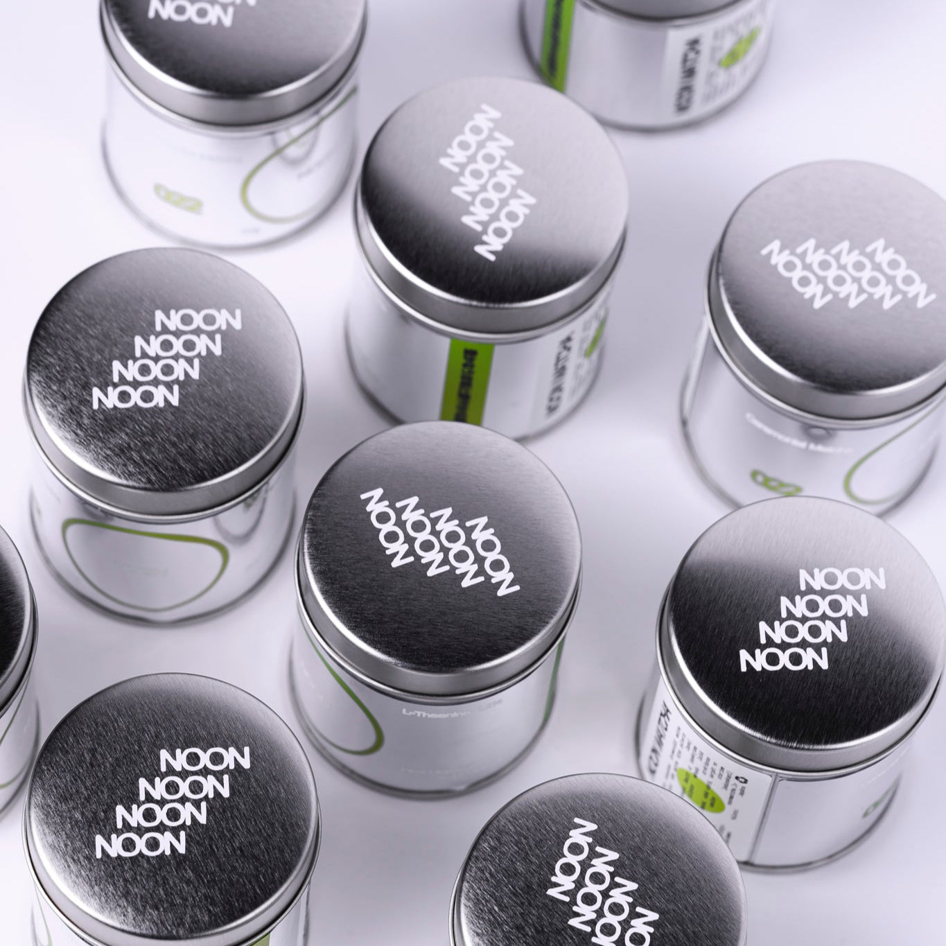 Matča tējas bundžas ar NOON logo uz balta fona