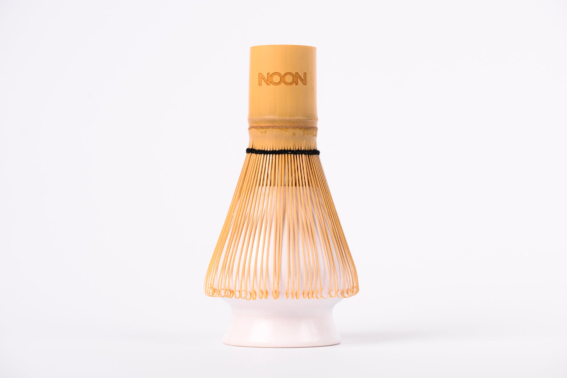 Gaiši brūna matcha bambusa slotiņa ar NOON logo uzlikta uz slotiņas turētāja