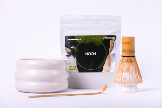 Matcha tējas komplekts ar piederumiem (bļoda, slotiņa, turētājs, karotīte) un ceremoniālā matcha 100g iepakojums uz balta fona