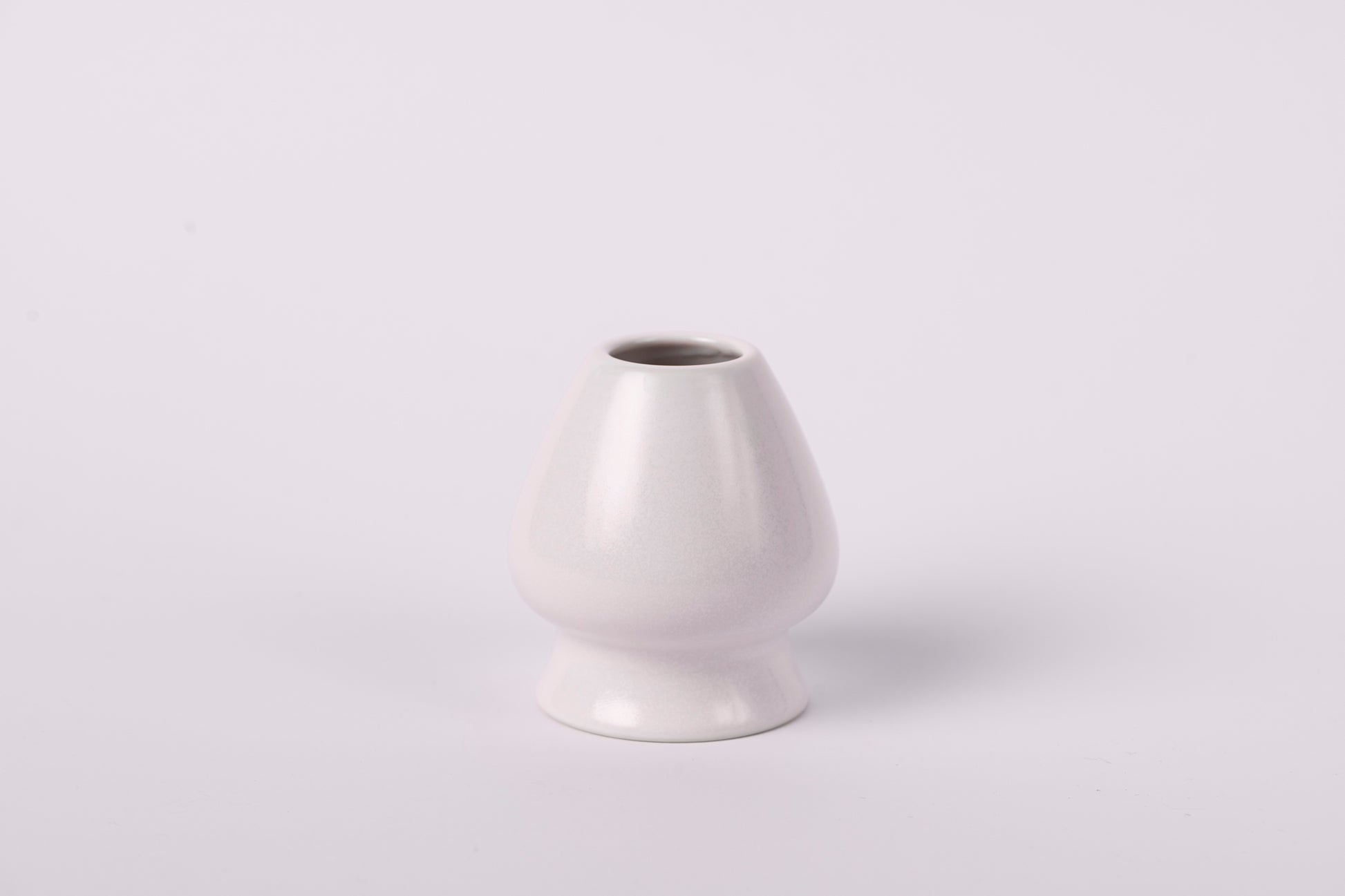 Krēmīgi balts keramisks matcha slotiņas turētājs uz balta fona