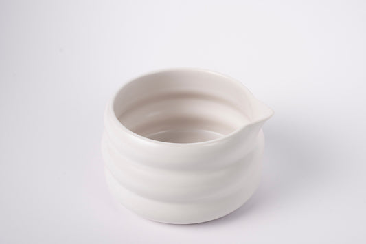 Krēmīgi balta keramiska matcha bļoda no augšas uz balta fona